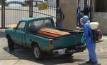 Funcionário de cemitério desinfeta caixão trazido em uma caminhonete pela própria família da vítima em Guayaquil, no Equador