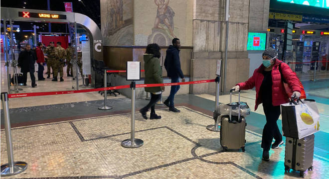 Mulher se protege com máscara ao caminhar pela estação de trem de Milão. Itália se prepara para declarar quarentena em toda a Lombardia
