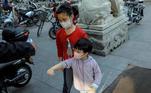 Crianças com máscara passeiam em rua de Pequim, China, durante a pandemia de covid-19
