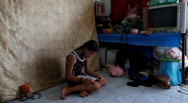 Menina, moradora da favela Klong Toey em Bangkok, na Tailândia, tenta estudar