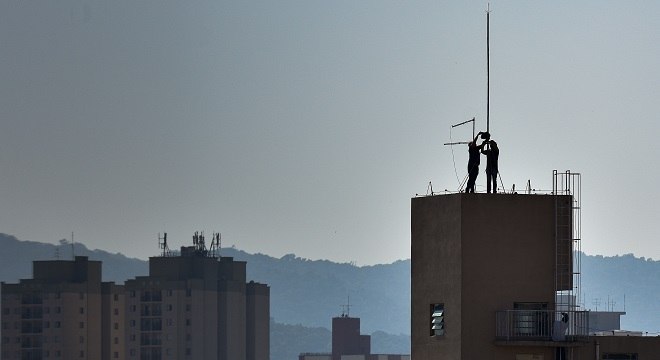 Homens trabalham em para-raios no alto de um prédio na zona norte de SP