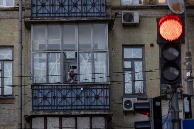 Na janela de um prédio, homem fala ao telefone
