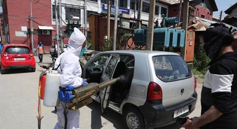 Funcionário aplica spray desinfetante em carro para combater a pandemia