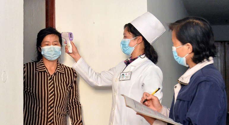 Agentes de saúde norte-coreanas aferindo temperatura da população