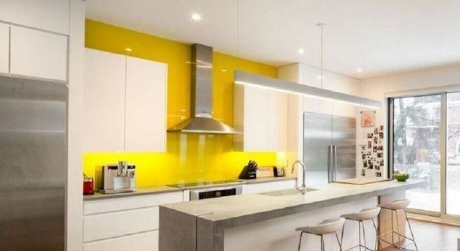 cozinha amarela e branca ampla decorada com ilha de cimento queimado 