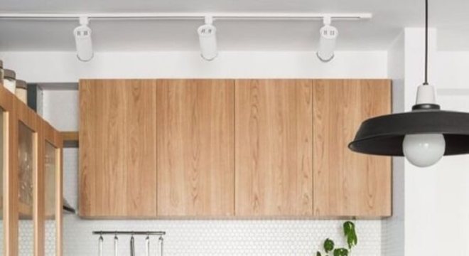 Cozinha com armário e bancada de madeira e Spot de trilho em tom branco