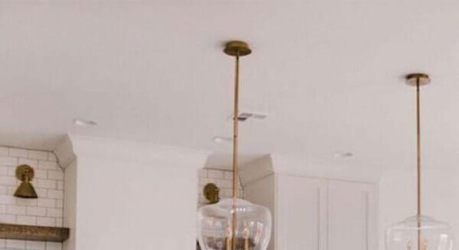 cozinha com ilha toda branca decorada com parede de tijolinho e banquetas minimalistas 