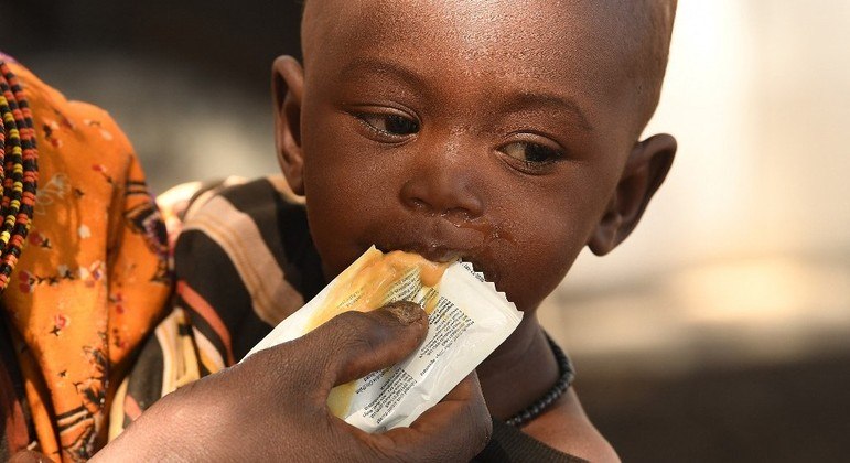 Mãe alimenta seu filho com pasta de amendoim rica em nutrientes, no Quênia