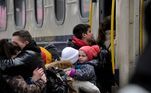 Mãe segura um bebê de colo antes de entrar no trem em Kiev, capital da Ucrânia, neste domingo (6)