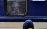 Em Kiev, garotinha dentro do trem faz careta para o homem que está do lado de fora