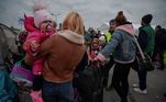 Mãe segura criança no colo na chegada a Medyka, cidade polonesa que faz fronteira com a Ucrânia