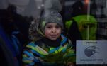 Criança sorri dentro de um ônibus após cruzar a fronteira da Ucrânia com a Polônia neste domingo (6)