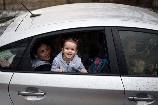 Criança ucraniana sorri na janela do carro a caminho da Polônia