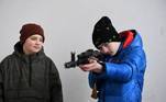 Crianças aprendem a manusear um AK-47 durante treinamento de defesa pessoal na cidade de Lviv, na Ucrânia