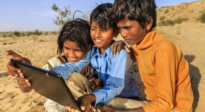 CrianÃ§as olham sorrindo para tablet na Ãndia
