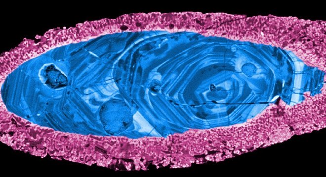 Cristal de zircão usado para datar o impacto do asteroide — a margem (rosa) recristalizou durante o impacto, deixando o núcleo interno (azul) intacto