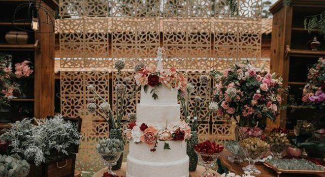 Decoração com folhagens na mesa de bolo de casamento