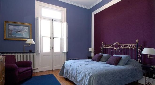 Decoração de quarto de casal com parede roxa e tapete azul