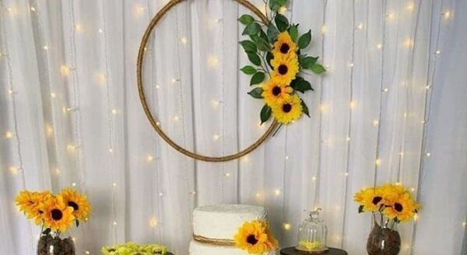 Decoração simples para festa tema girassol com cortina de pisca pisca e mesa de madeira