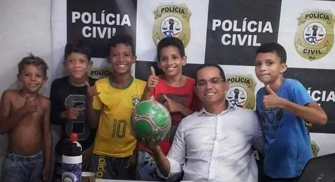 Garotos ao lado de delegado com bola nova em Presidente Dutra (MA)
