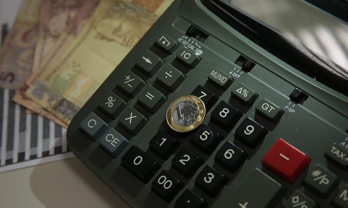 Dinheiro, cédulas e moedas de reais e uma calculadora. Agência Brasil/Marcello Casal Jr.