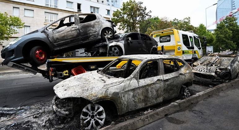 Carros que foram destruídos durante a noite são recolhidos das ruas