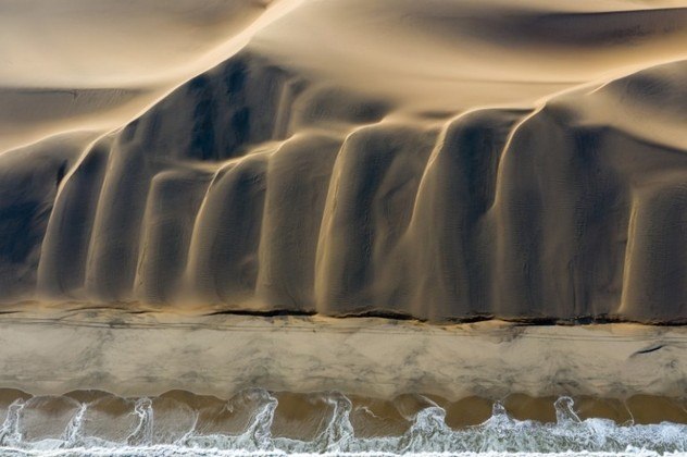 O fotógrafo suíço David Rouge venceu a categoria Natureza ao mostrar o encontro do oceano com o deserto. Com a ajuda do drone, o fotógrafo conseguiu exibir o formato das dunas de areia, que lembram montanhas, lado a lado da faixa de areia e do mar do oceano Atlântico Sul