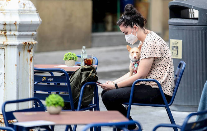 -FOTODELDIA- GRAFCAV6921. SAN SEBASTIÁN (ESPAÑA), 23/07/2021.- Una joven toma una consumición protegida con mascarilla este viernes en una terraza de San Sebastián. El decreto del lehendakari que impone un mayor uso de la mascarilla en espacios exteriores y limita los horarios en hostelería y en actividades culturales y sociales ha sido publicado este viernes en el Boletín Oficial del País Vasco (BOPV), de manera que ya está en vigor. EFE/Juan Herrero.