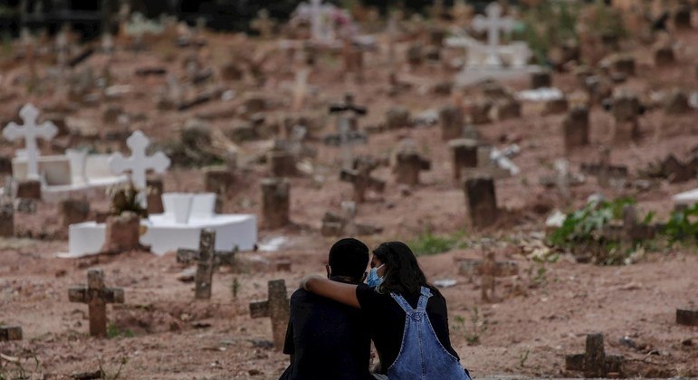 Um casal chorando pela morte de uma mulher, sepultada em um cemitério do Rio de Janeiro