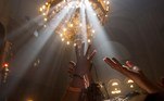 Jerusalem (---).- Orthodox Christian worshippers raise their hands to the light that illuminates the golden lamps in the Church of the Holy Sepulchre in Jerusalem, 30 April 2016 (reissued 27 May 2020). Gold is considered a majestic color that symbolizes wealth and luxury. It is associated with success, achievement, and triumph, but it can also be deemed decadent and overindulgent. Connected with prestige and elegance, gold symbolizes divinity, power, and wisdom in many religions due to its association with masculine energy and the power of the sun. (Estados Unidos, Jerusalén) EFE/EPA/ATEF SAFADI ATTENTION: This Image is part of a PHOTO SET *** Local Caption *** 52731640
