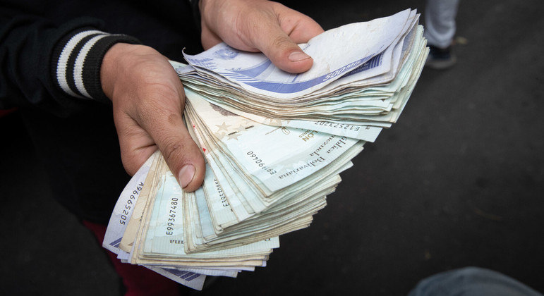 Trabalhador público mostra bolo de dinheiro que equivale a R$ 27 na Venezuela