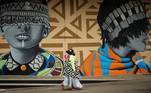 Johannesburg (Sudáfrica), 02/10/2020.- Una madre carga a su hijo en la espalda mientras pasa junto a obras de arte de graffiti en las paredes en el moderno distrito de Maboneng en Johannesburgo, Sudáfrica, 02 de octubre de 2020. EFE/EPA/KIM LUDBROOK