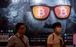 FOTODELDÍA-Hong Kong (China), 25/09/2021.- Dos hombres pasan junto a un cartel publicitario de Bitcoins y criptomonedas en Hong Kong, China, el 25 de septiembre de 2021. El 24 de septiembre, China intensificó la represión de las criptomonedas con una prohibición general de todas las transacciones de criptomonedas, afectando a bitcoin y otras monedas importantes. EFE/EPA/JEROME FAVRE