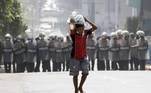 Yangon (Myanmar), 26/02/2021.- A boy carries a sack of rice past anti-riot police officers blocking a road during a protest against the military coup, in Yangon, Myanmar, 26 February 2021 Anti-coup protests continue in Myanmar amid regional diplomatic attempts to reach a resolution to weeks of unrest caused by the military coup. (Protestas, Golpe de Estado, Birmania) EFE/EPA/LYNN BO BO