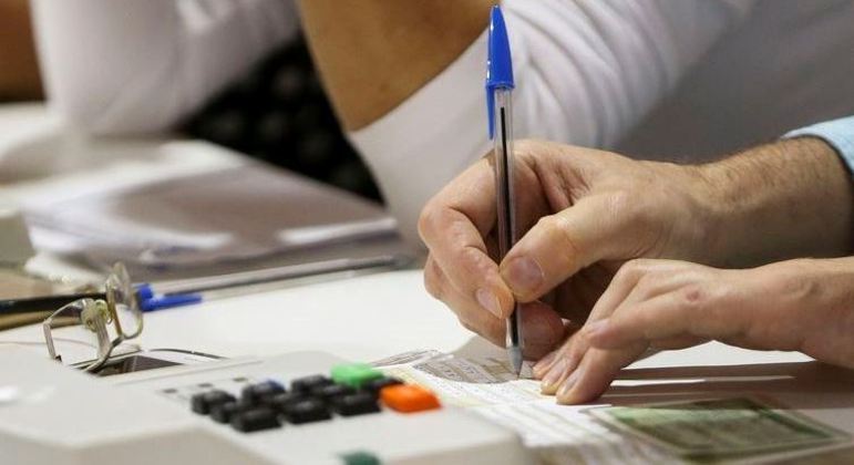 Mesário anotando dados do eleitor em seção eleitoral durante as Eleições 2022