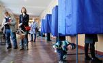 Um menino espera enquanto sua mãe vota durante as eleições locais realizadas durante a pandemia de coronavírus  em Kiev, Ucrânia. Ucranianos em todo o país dirigiram-se às urnas para as eleições locais.