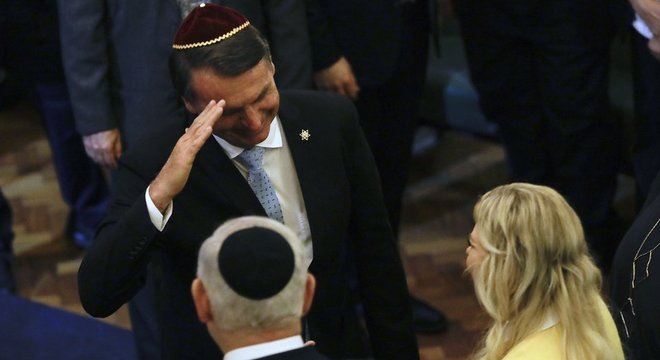Em foto de dezembro, Bolsonaro cumprimenta Benjamin Netanyahu e sua mulher em visita do premiê ao Rio; agora, é o brasileiro quem viaja a Israel