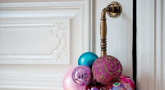 Enfeite de natal para porta feito com bolas coloridas e posicionado na maçaneta da porta