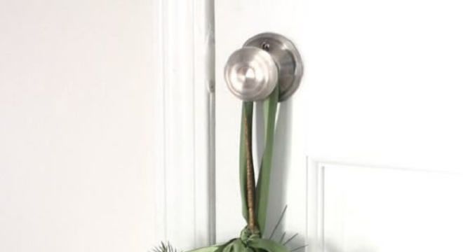 Enfeite de natal para porta feito com ramos e posicionado na maçaneta