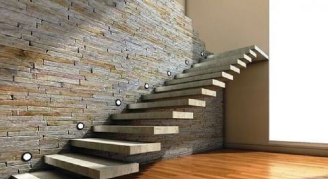 Escada flutuante de concreto com pontos de luz fixada em uma parede de pedra