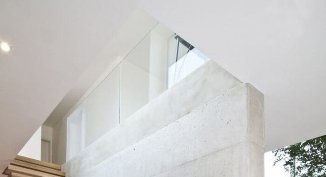 Escada flutuante de madeira clara fixada em parede de concreto