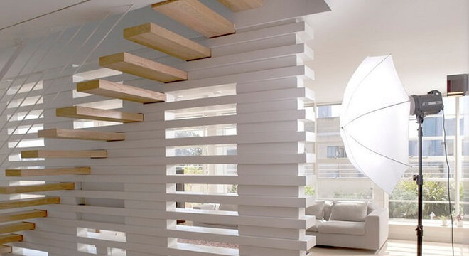 Escada flutuante de madeira clara se harmoniza com a parede branca