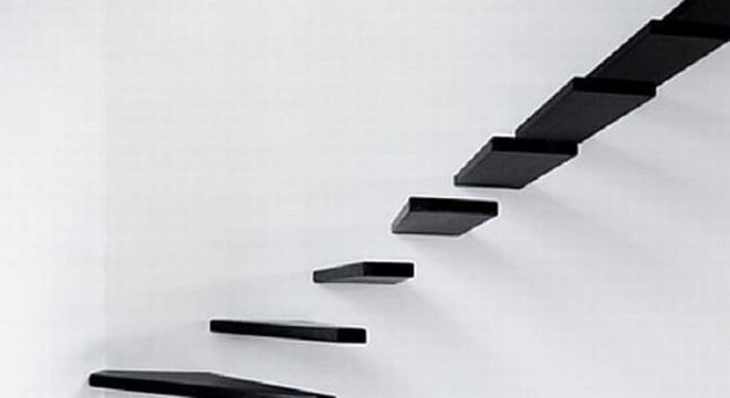 Escada flutuante de madeira preta fixada a uma parede branca