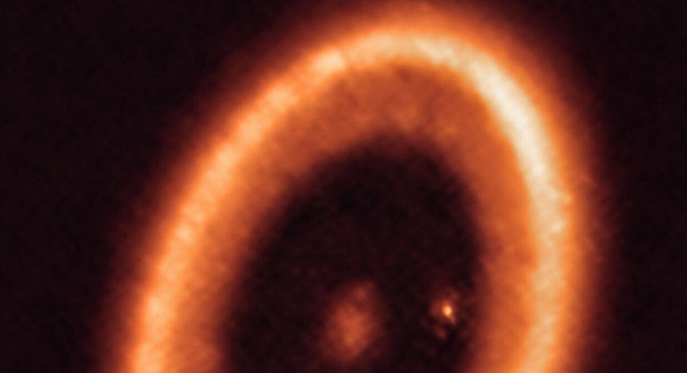 A imagem apresentada foi obtida em 2021, pelo Atacama Large Millimeter Array. Os cientistas acreditam que essa mancha difusa seja um disco de poeira, que está formando uma espécie de lua
