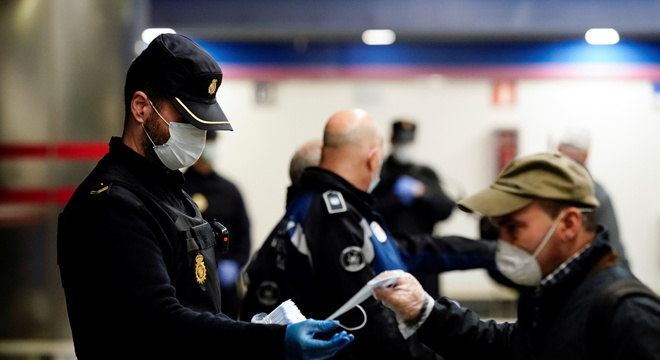 Policial espanhol distribui máscaras: país planeja saída lenta da quarentena para maio