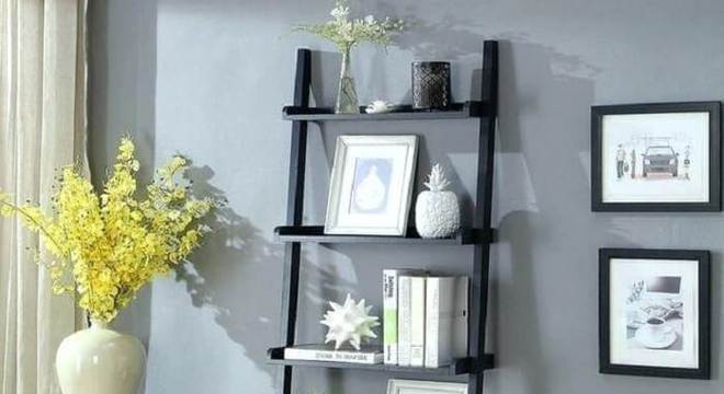 Estante escada preta serve de apoio para itens decorativos da sala de estar