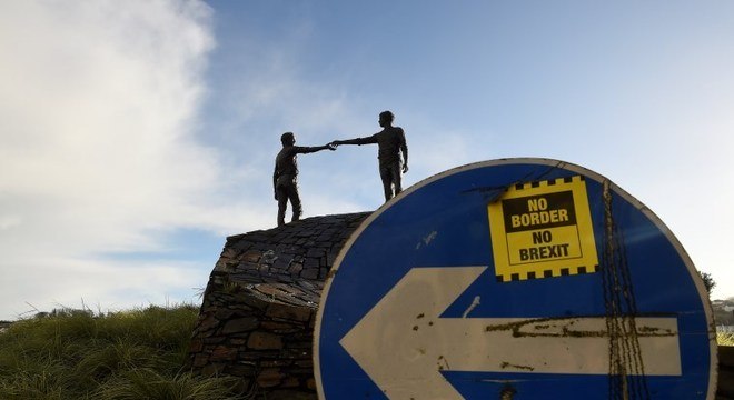 Monumento em homenagem à paz nas Irlandas e adesivo 'sem fronteira, sem Brexit'