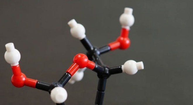 Um pedaço do meteorito Murchison ao lado do que seria a estrutura molecular da ribose, um dos açúcares encontrados em sua poeira