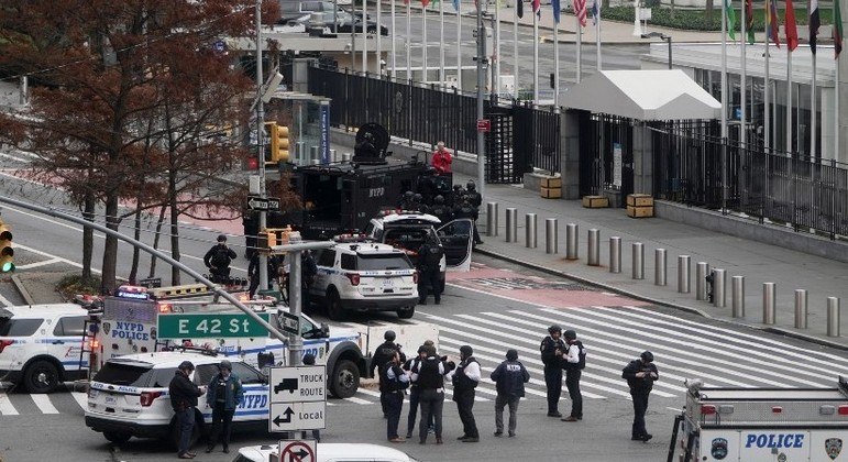 Vestido de vermelho, homem armado conversa com policiais diante da ONU, em Nova York