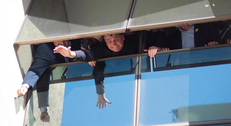 Ex-presidente Jair Bolsonaro acena a apoiadores de uma janela na sede do PL, no Brasil 21, em Brasília